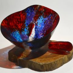 Fused bowl in blues, reds on a wooden slab